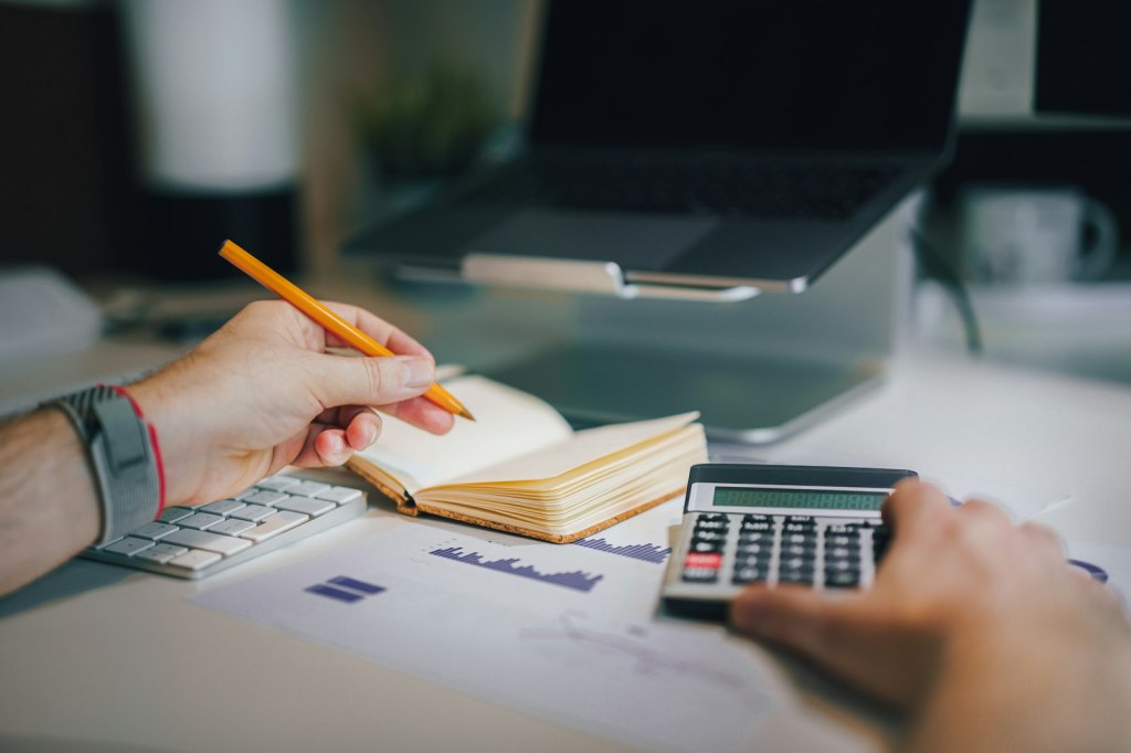 A person at a desk working with a calculator and notebook