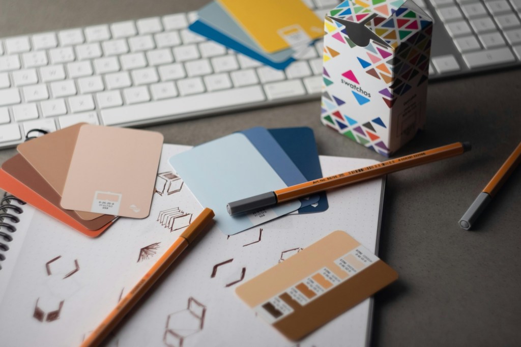A designer's desk with colour swatches, pencils and a keyboard