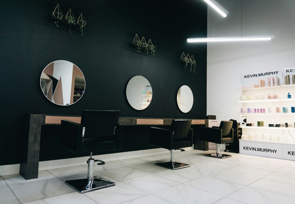 Black salon chairs facing round mirrors in a modern hair salon