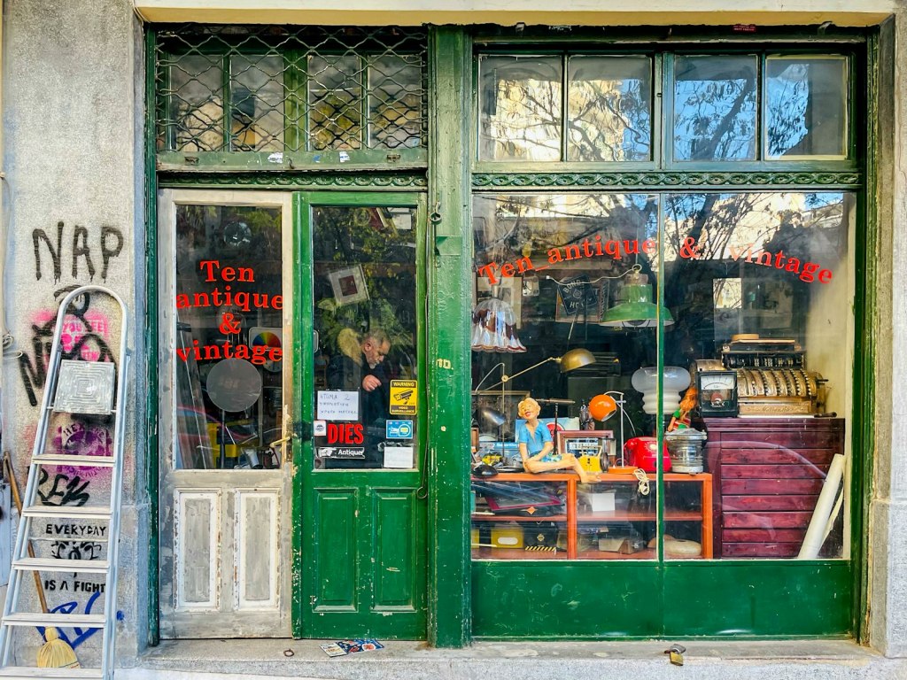 An independent shop with a green painted door and window full of goods